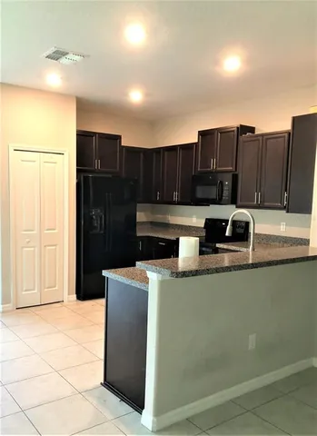 a kitchen with kitchen island granite countertop a sink dishwasher stove and cabinets