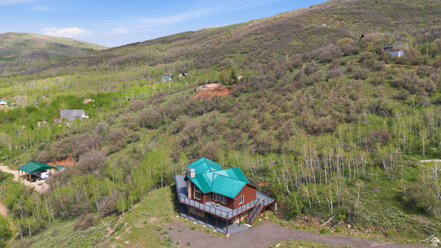 6 Beaver Springs Rancheros Oakley, UT 84055 - Photo 57 of 68 Elevated property featuring a vibrant green metal roof, red siding, and an expansive multi-level deck