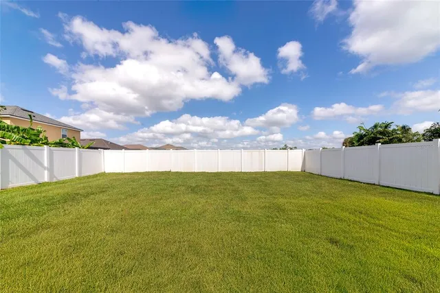 a view of yard with swimming pool and wooden fence