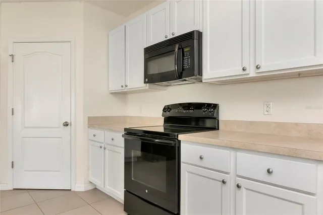 a kitchen with white cabinets and black appliances