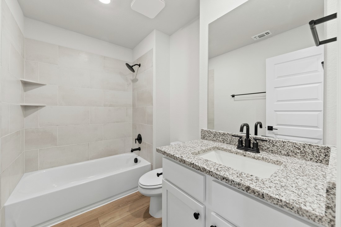 9509 Demure Drive, Unit 4 Manor, TX 78653 - Photo 13 of 21 a bathroom with a granite countertop sink a toilet and bathtub