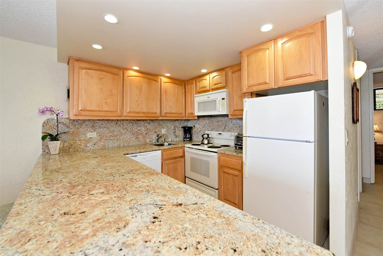 3543 Lower Honoapiilani Road, Unit L302 Lahaina, HI 96761 - Photo 14 of 28 a kitchen with a refrigerator a stove top oven a sink and cabinets