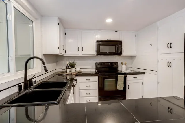 a kitchen with stainless steel appliances a stove sink and white cabinets