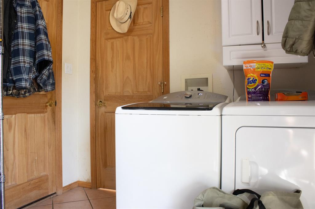 140 Baize Road Abilene, TX 79602 - Photo 21 of 37 Laundry room with cabinet space, washing machine and dryer, and light tile patterned floors
