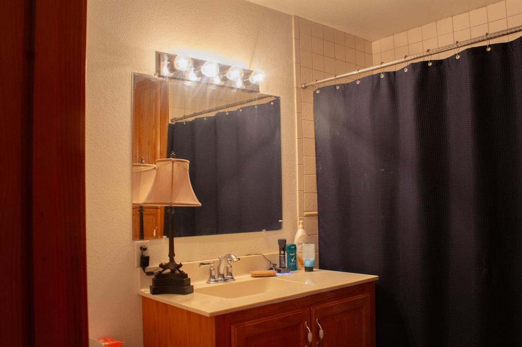 140 Baize Road Abilene, TX 79602 - Photo 25 of 37 Full bathroom with vanity, curtained shower, and a textured wall
