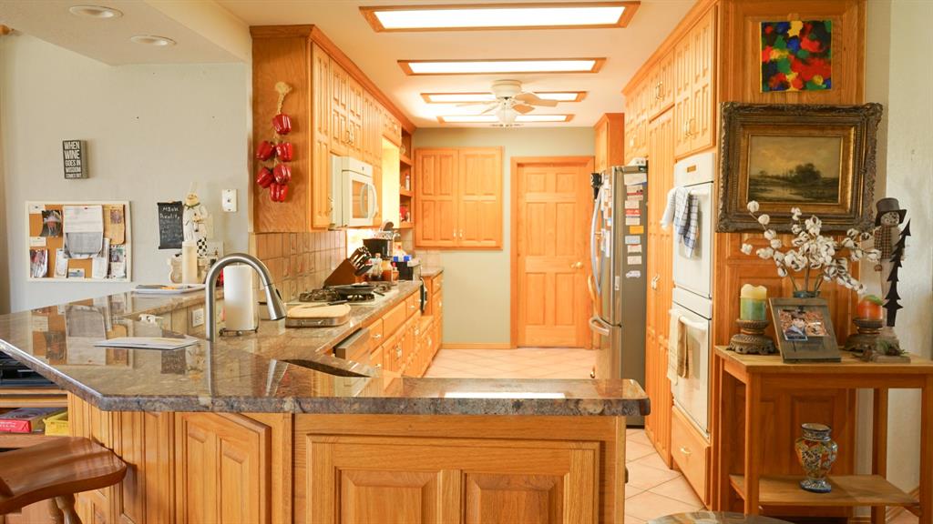 140 Baize Road Abilene, TX 79602 - Photo 5 of 37 Kitchen featuring a peninsula, tasteful backsplash, stainless steel appliances, light tile patterned flooring, and a kitchen breakfast bar