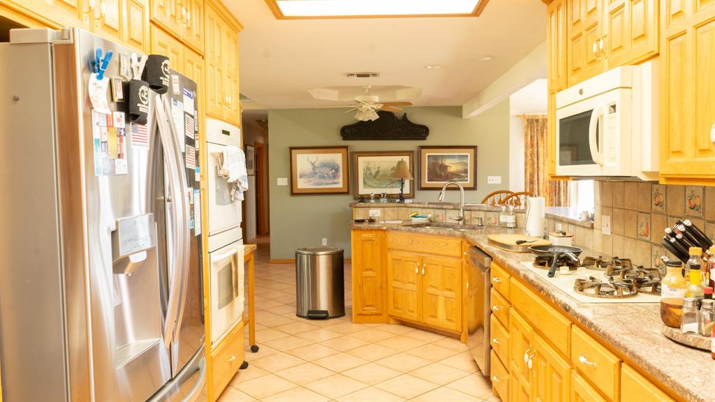 140 Baize Road Abilene, TX 79602 - Photo 6 of 37 Kitchen with stainless steel appliances, backsplash, ceiling fan, light wood finish cabinetry, and light stone counters