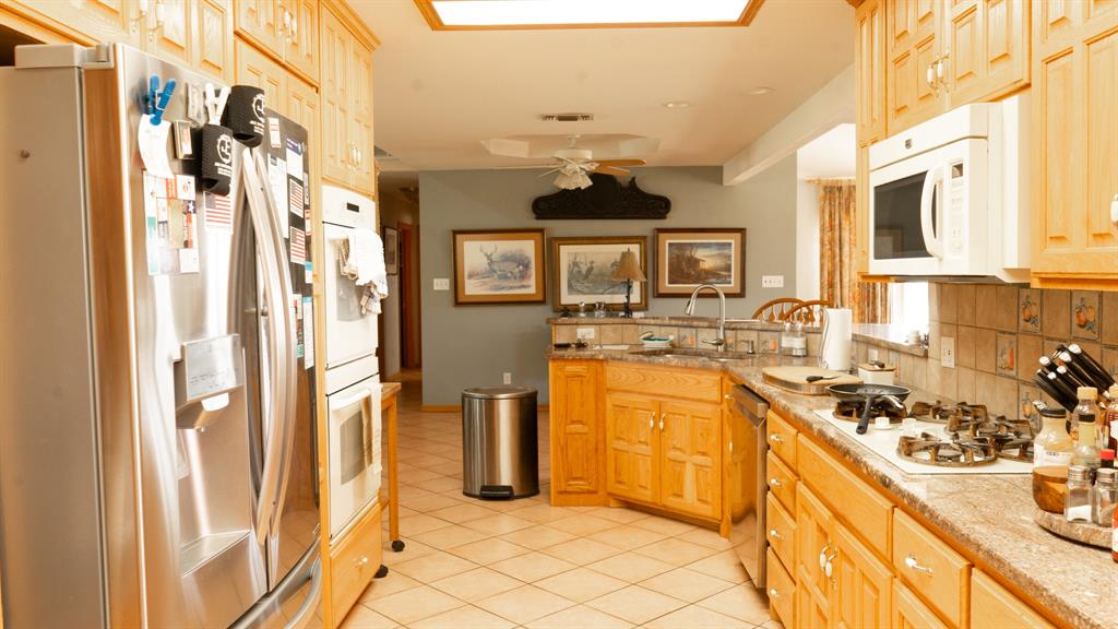 140 Baize Road Abilene, TX 79602 - Photo 7 of 37 Kitchen featuring stainless steel appliances, backsplash, light wood finish cabinetry, ceiling fan, and a peninsula
