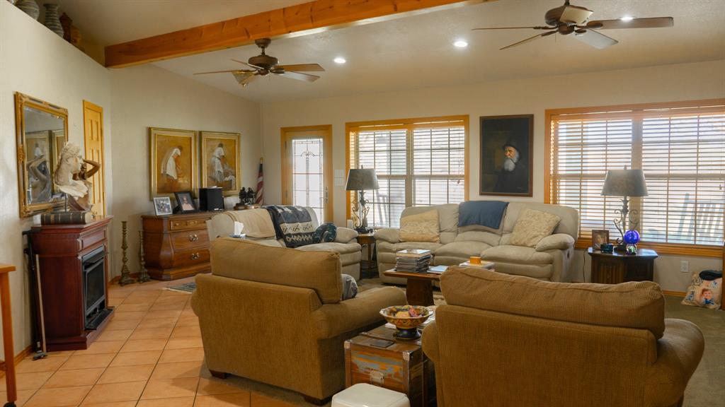 140 Baize Road Abilene, TX 79602 - Photo 8 of 37 Tiled living area featuring a ceiling fan, vaulted ceiling with beams, recessed lighting, and a glass covered fireplace