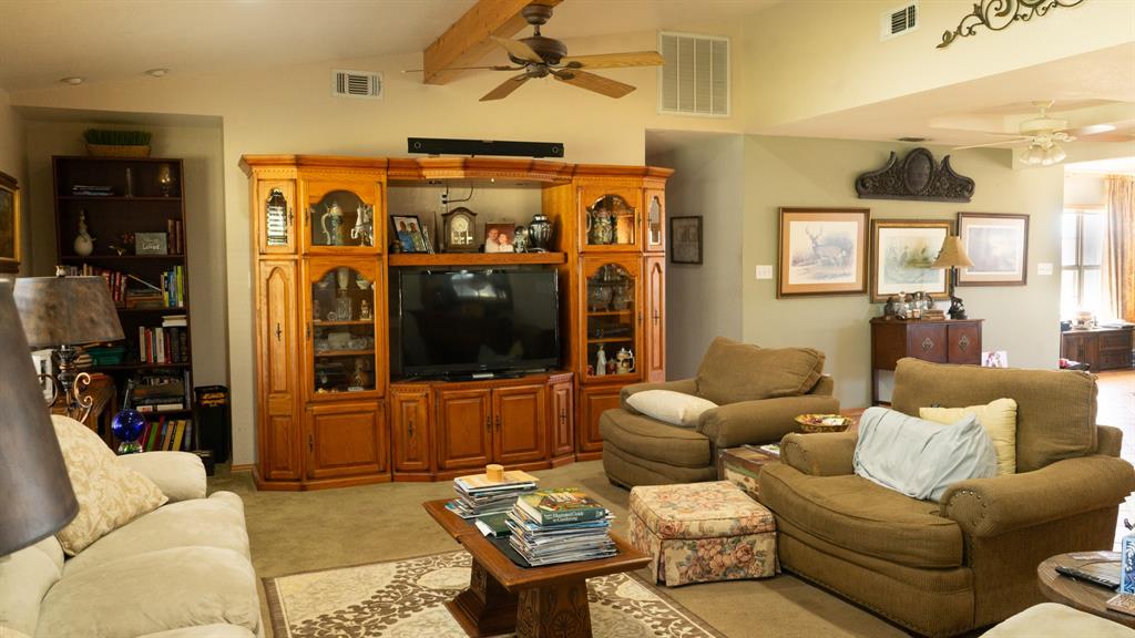140 Baize Road Abilene, TX 79602 - Photo 9 of 37 Living area featuring a ceiling fan, vaulted ceiling with beams, and light colored carpet