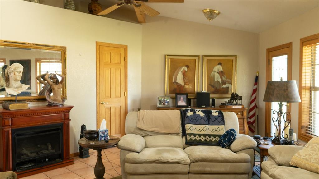 140 Baize Road Abilene, TX 79602 - Photo 10 of 37 Living room featuring healthy amount of natural light, a fireplace, tile patterned flooring, a ceiling fan, and vaulted ceiling
