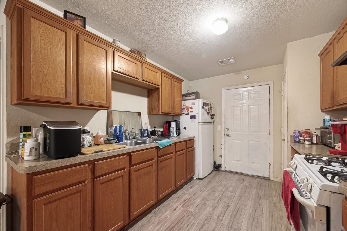 7100 Harlem Street Baytown, TX 77521 - Photo 13 of 30 a kitchen with stainless steel appliances granite countertop a refrigerator a sink dishwasher a stove and white countertops with wooden floor