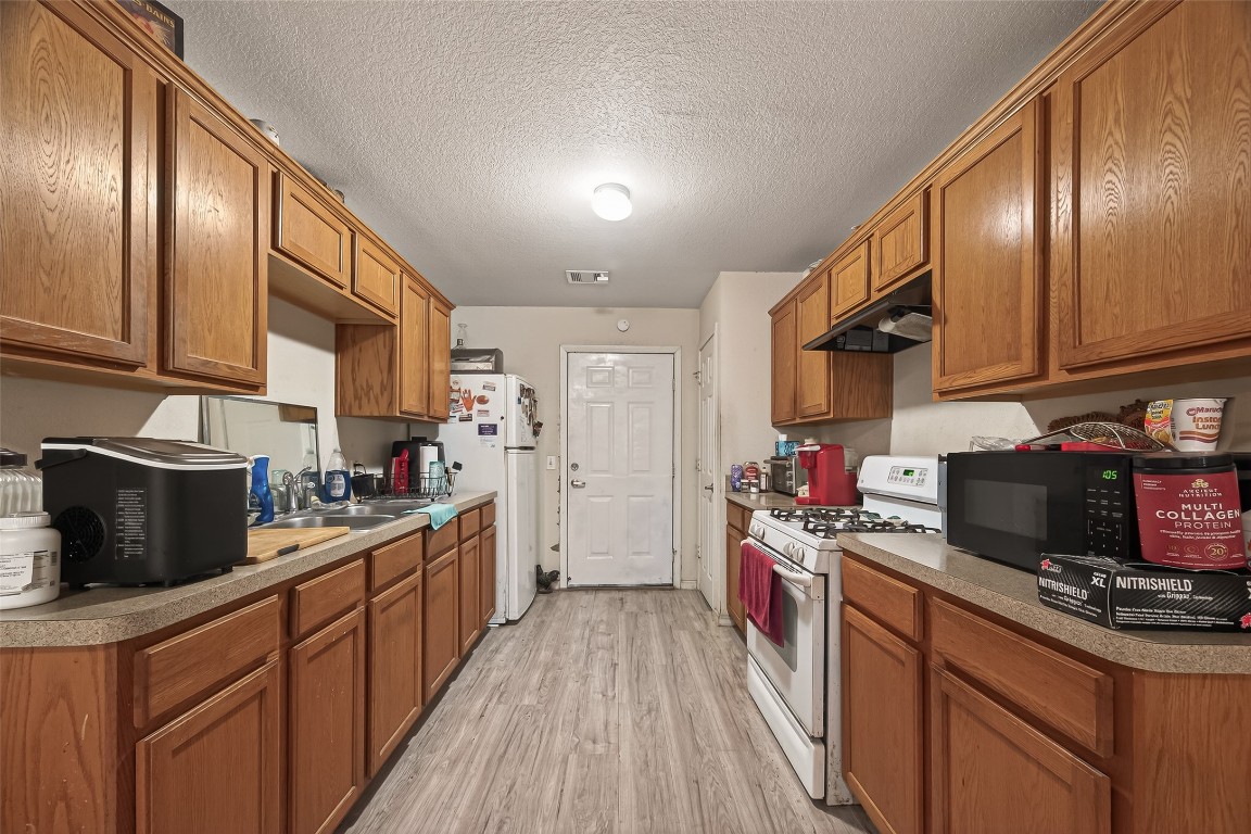 7100 Harlem Street Baytown, TX 77521 - Photo 14 of 30 a kitchen with stainless steel appliances granite countertop a stove a sink dishwasher and cabinets with wooden floor