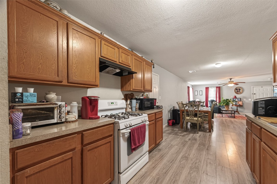 7100 Harlem Street Baytown, TX 77521 - Photo 17 of 30 a kitchen with stainless steel appliances granite countertop a stove top oven a sink dishwasher a dining table and chairs with wooden floor