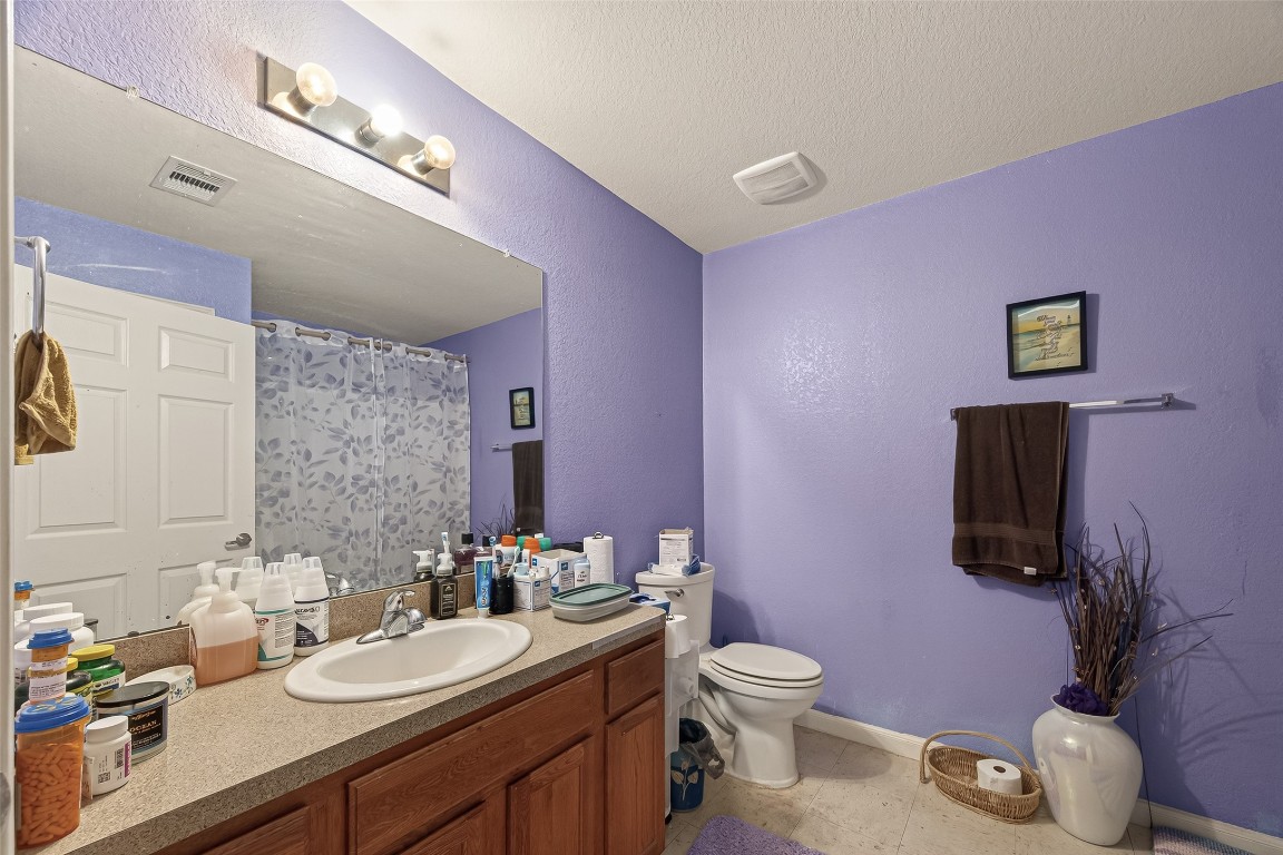 7100 Harlem Street Baytown, TX 77521 - Photo 25 of 30 a bathroom with a granite countertop toilet sink and mirror