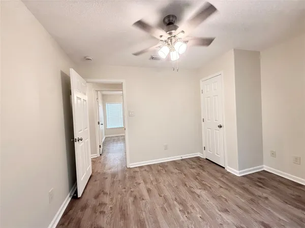 an empty room with wooden floor and ceiling fan
