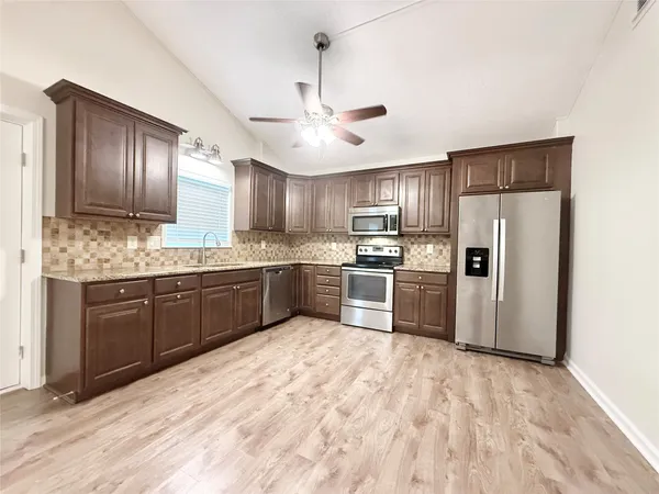 a kitchen with granite countertop stainless steel appliances cabinets a sink and a counter top space