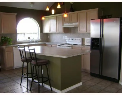 a kitchen with stainless steel appliances granite countertop a stove a refrigerator a sink a dining table and chairs with wooden floor