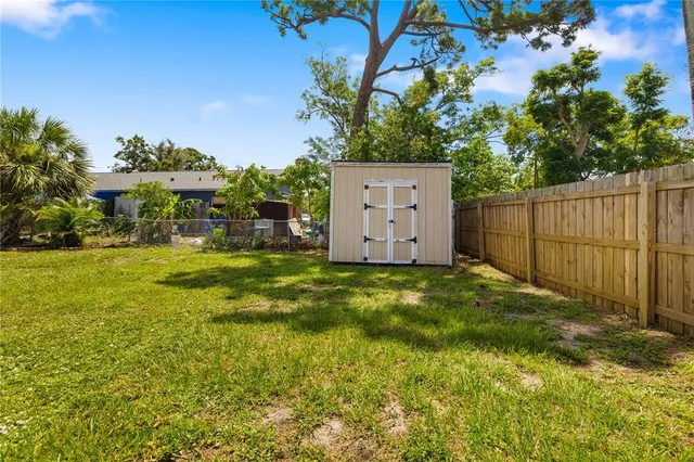 a view of a backyard with plants and white fence