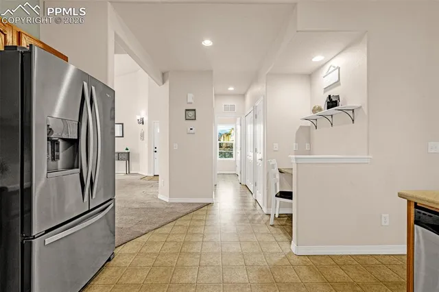 a view of a refrigerator in kitchen and an empty room