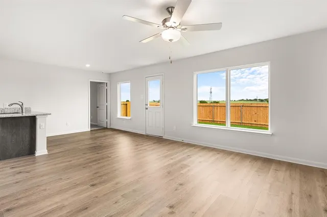 a view of an empty room with window and wooden floor