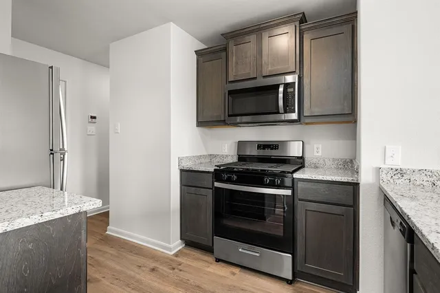 a kitchen with stainless steel appliances granite countertop a stove microwave and sink