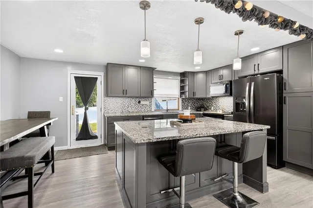 a kitchen with stainless steel appliances granite countertop a sink a stove a refrigerator cabinets a dining table and chairs