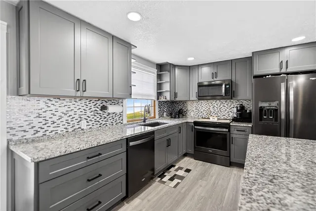 a kitchen with kitchen island granite countertop a sink stove and refrigerator