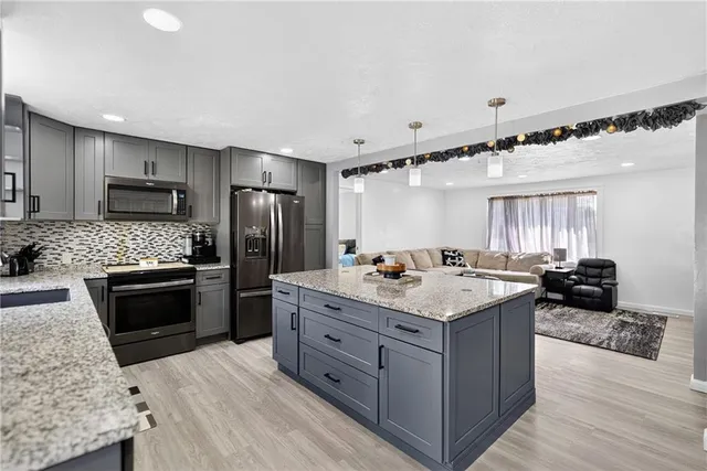 a kitchen with stainless steel appliances kitchen island granite countertop a stove refrigerator and a sink