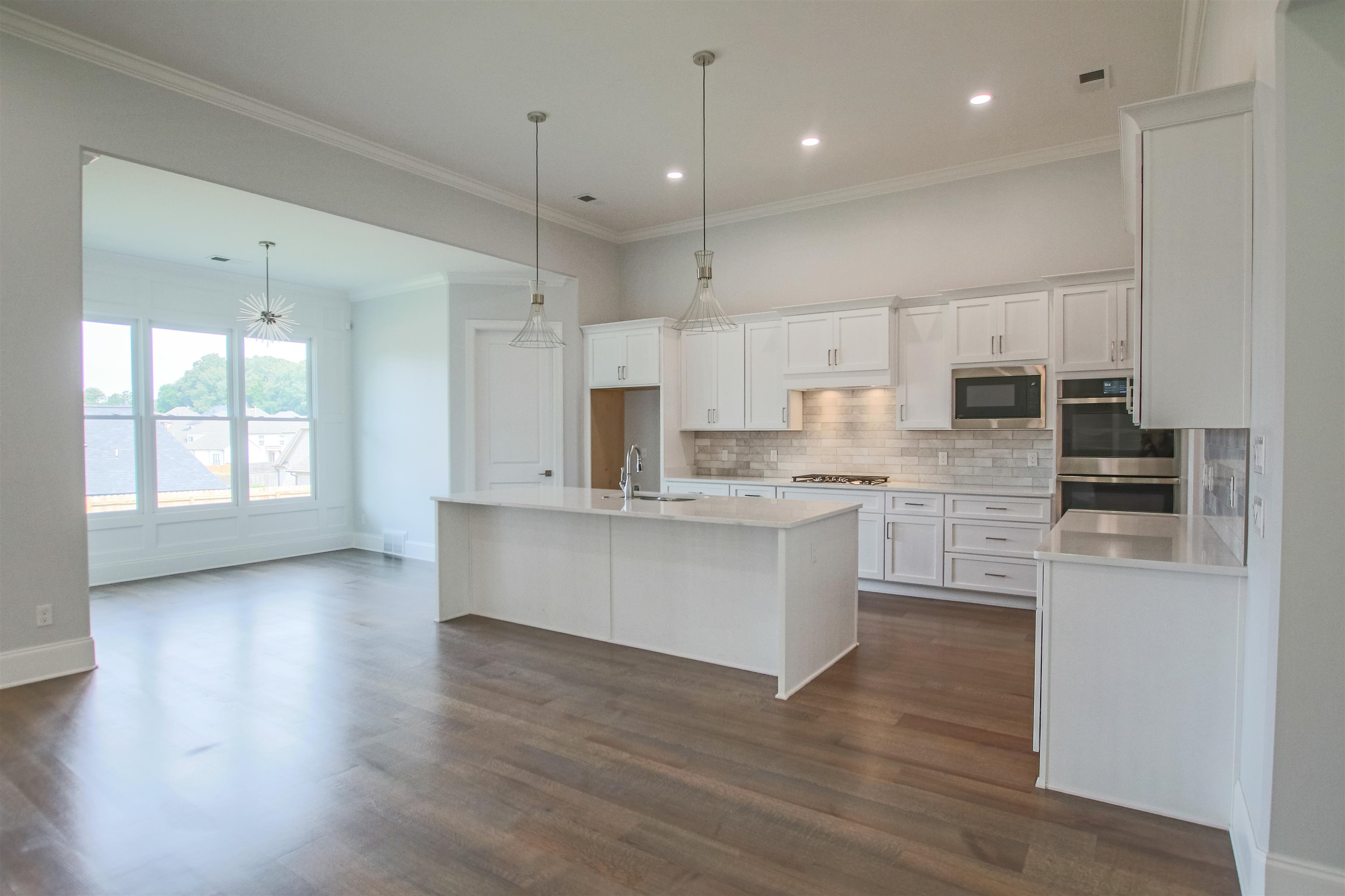2611 Moore Road Germantown, TN 38138 - Photo 17 of 35 Kitchen featuring tasteful backsplash, white cabinets, a kitchen island with sink, dark hardwood / wood-style floors, and stainless steel appliances