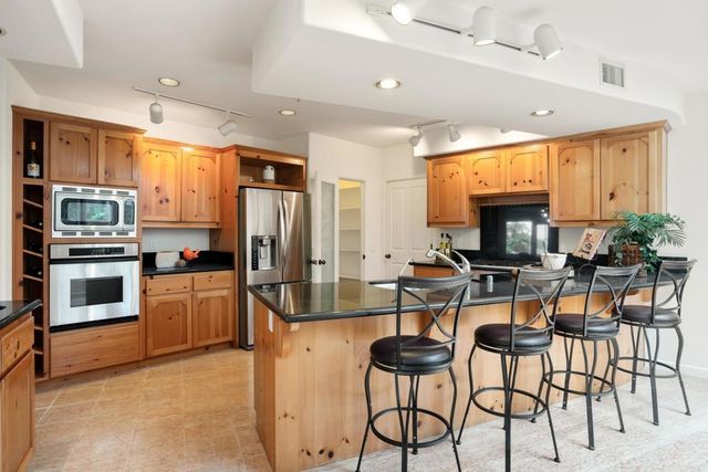 a kitchen with stainless steel appliances kitchen island granite countertop a stove and a refrigerator