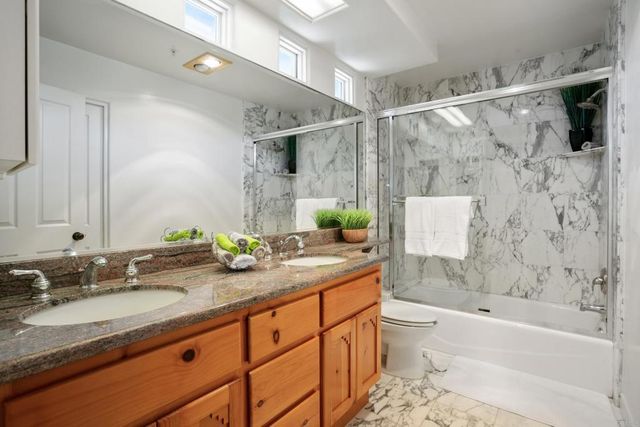 a bathroom with a granite countertop sink a toilet and shower