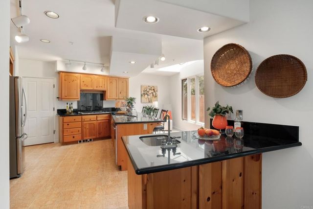 a kitchen with kitchen island granite countertop a sink a stove and a refrigerator