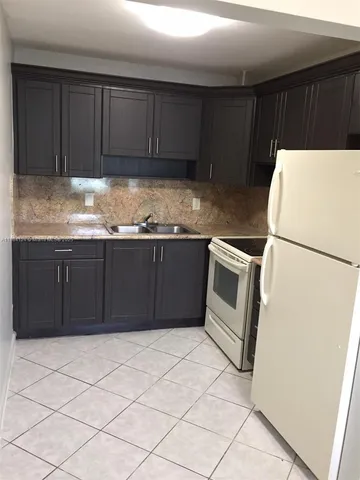 a kitchen with granite countertop a stove a refrigerator and a sink