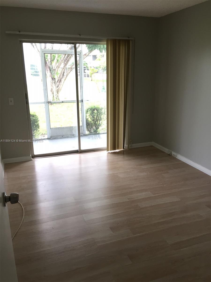 182 Markham I, Unit 182 Deerfield Beach, FL 33442 - Photo 6 of 7 a view of an empty room with wooden floor and a window