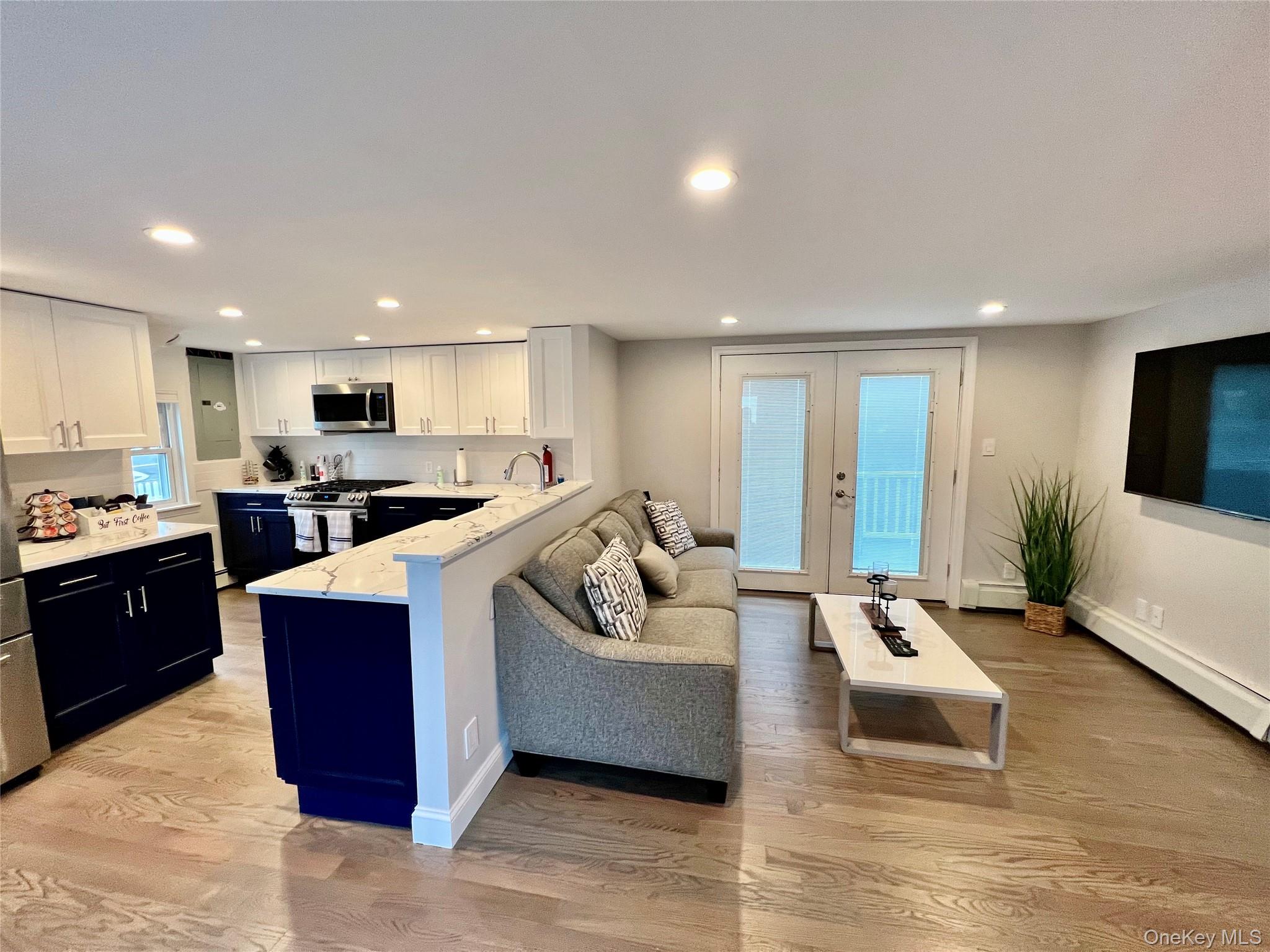 100 Clubhouse Road Bellmore, NY 11710 - Photo 9 of 18 Living area with light wood-style flooring, french doors, recessed lighting, and baseboard heating