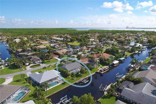 an aerial view of a house with a yard lake and trees all around