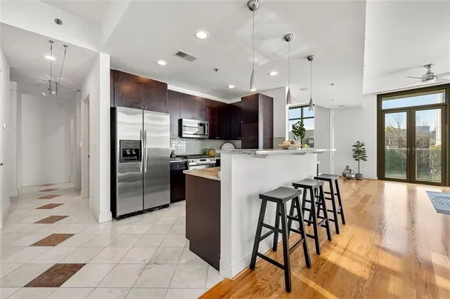 a kitchen with stainless steel appliances kitchen island granite countertop a refrigerator and a stove top oven