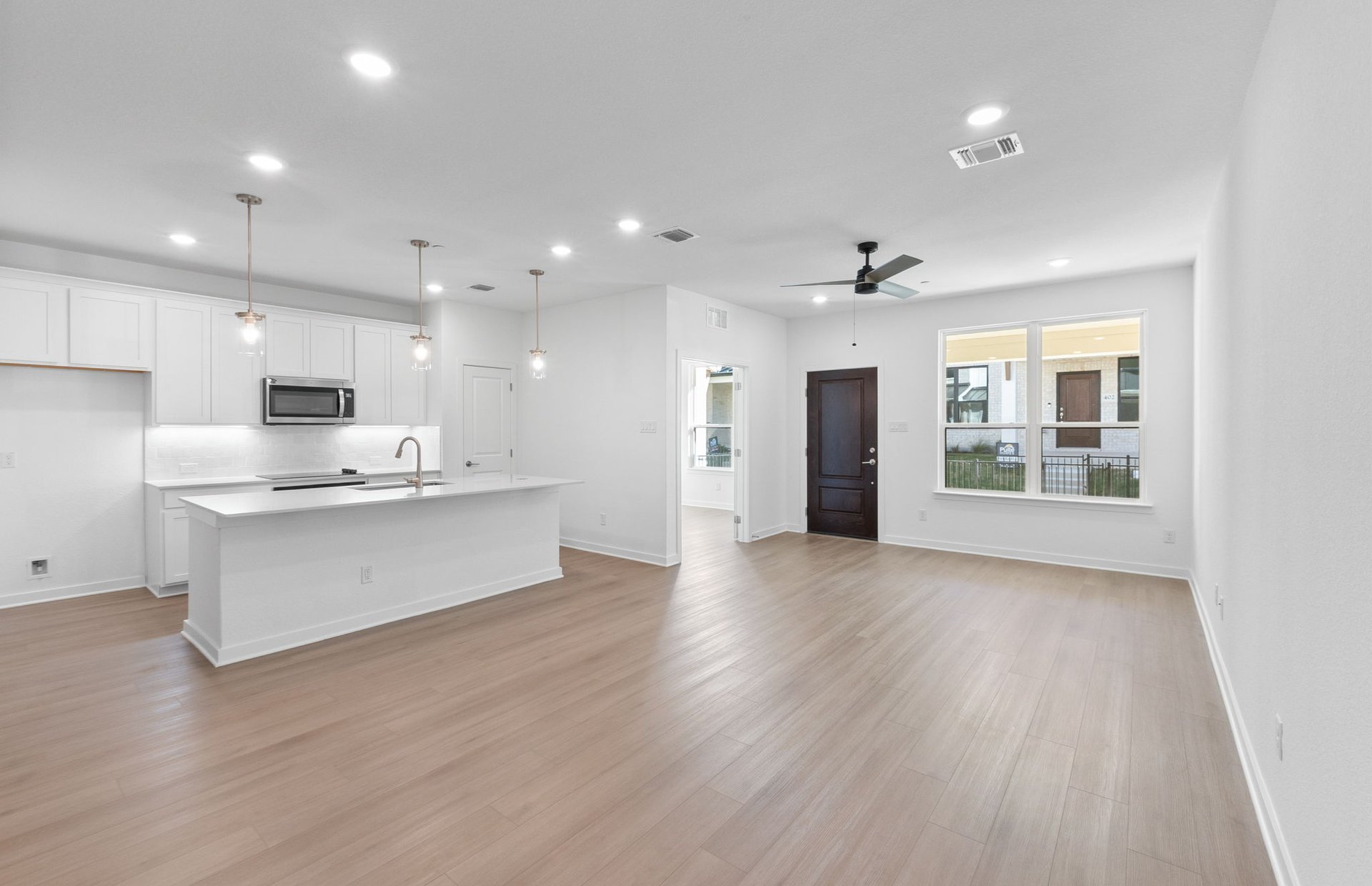 1280 East Main Street, Unit 602 Round Rock, TX 78664 - Photo 7 of 22 an open kitchen with white cabinets wooden floor and a refrigerator