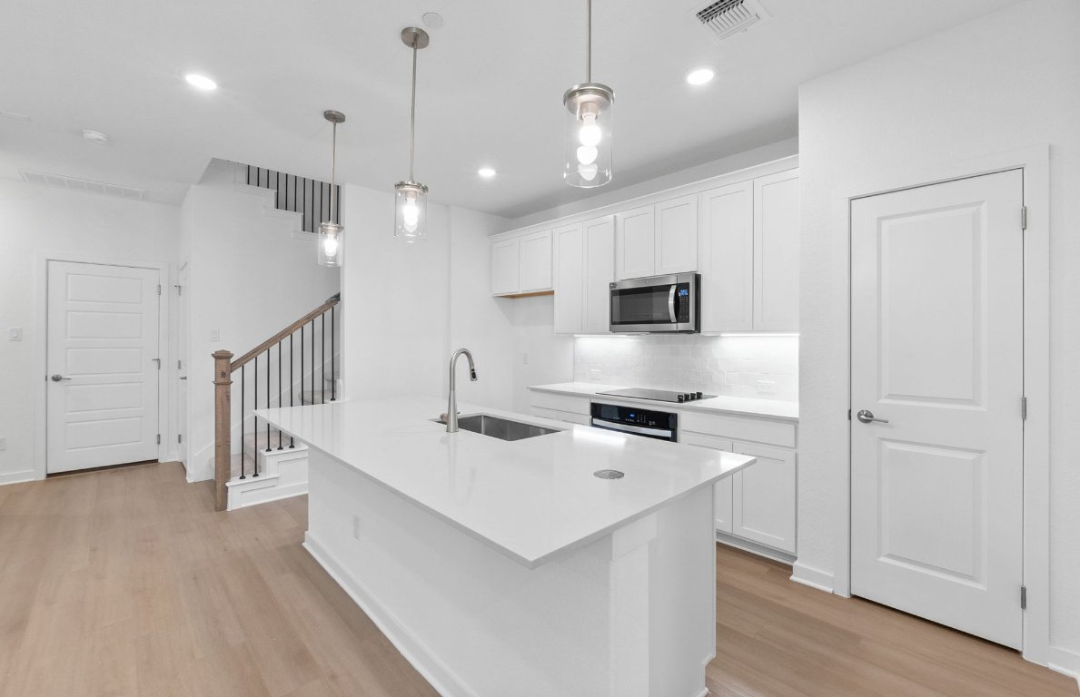 1280 East Main Street, Unit 602 Round Rock, TX 78664 - Photo 8 of 22 a kitchen that has a lot of cabinets a sink and wooden floor