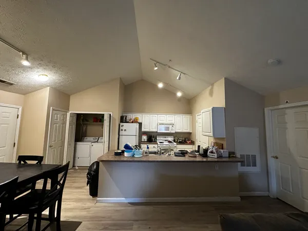 a kitchen with kitchen island granite countertop a refrigerator dining table and chairs