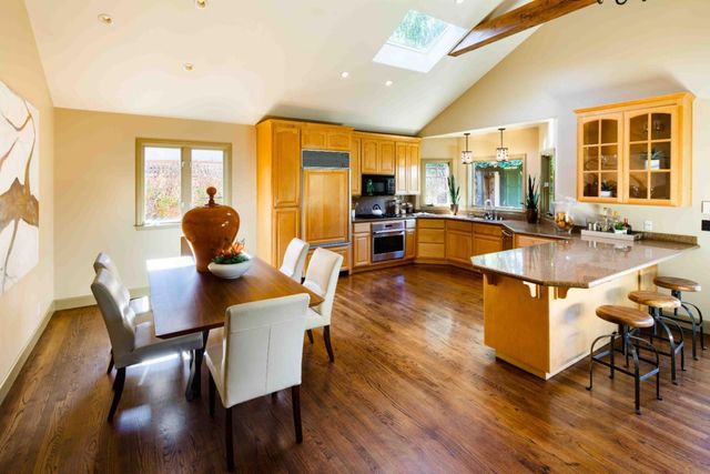 a dining room with wooden floor and large windows