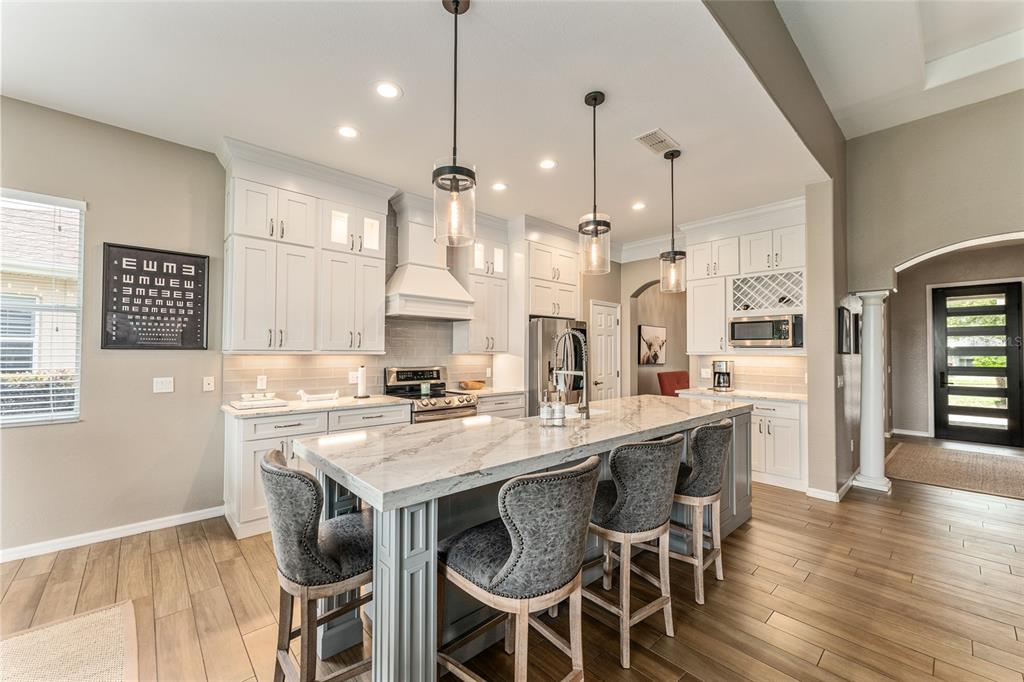 4958 Northwest 35th Ln Road Ocala, FL 34482 - Photo 30 of 66 a kitchen with stainless steel appliances granite countertop a table chairs stove and wooden floor