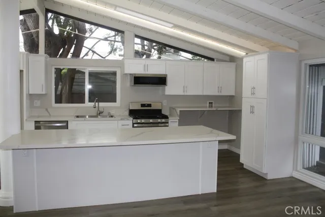 a view of a kitchen with stainless steel appliances granite countertop a sink and a stove