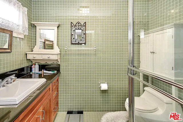 a bathroom with a sink a toilet a mirror and shower