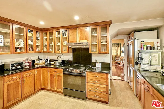 a kitchen with stainless steel appliances granite countertop a stove top oven a sink a refrigerator and cabinets