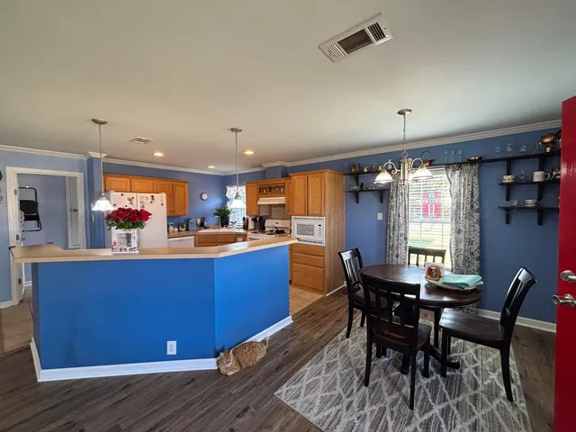 a kitchen with stainless steel appliances granite countertop a table chairs and a refrigerator
