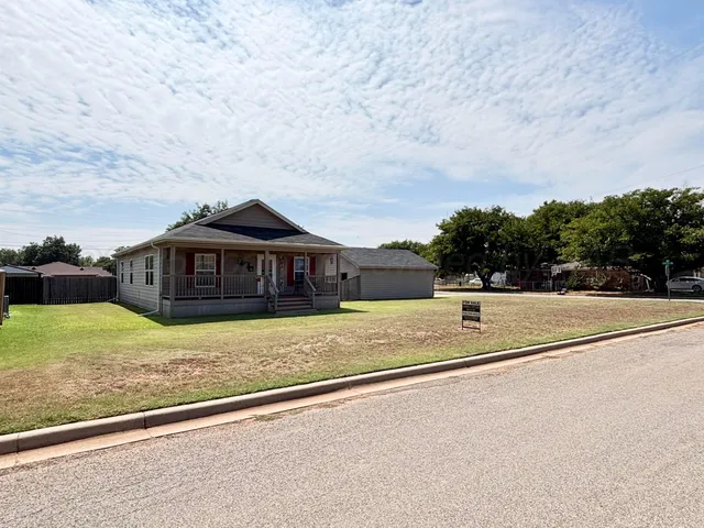 a view of a big house with a big yard and large trees