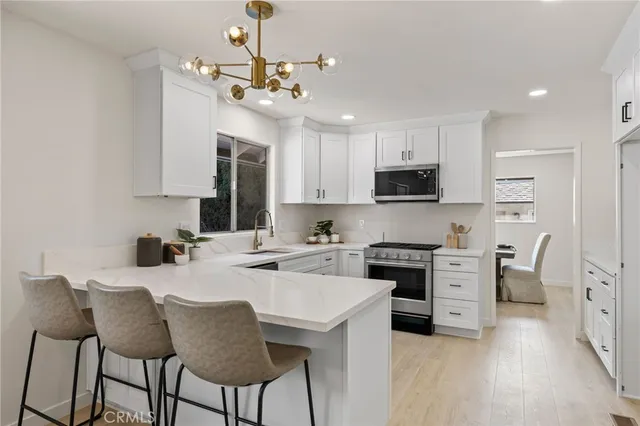 a kitchen with stainless steel appliances granite countertop a stove top oven a sink dishwasher and a refrigerator with wooden floor