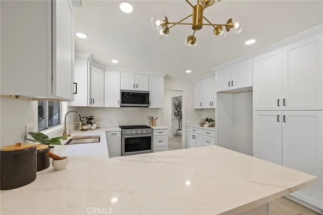 a kitchen with kitchen island a stove a refrigerator a sink and dishwasher with wooden floor